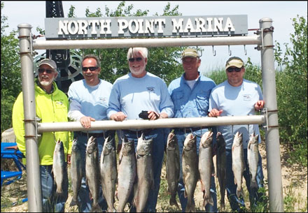 5 men standing behind rack holding 8 large fish