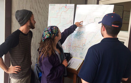 3 students observing large map on a stand